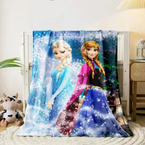Plaid la reine des neiges avec imprimé d'Elsa et Anna avec une peluche et une plante verte à gauche et une chaise avec une lampe posée sur un bureau à droite
