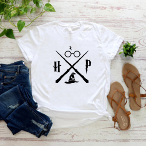 T-shirt Harry Potter doux et léger avec des tongs à droite un jean à gauche et une plante verte en haut sur un fond en bois